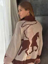 Campera de punto color beige con cuello polo marrón, cierre frontal y puños acanalados. Presenta un diseño con motivos ecuestres en color marrón en la parte trasera.