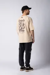 Remera color beige de corte oversize, con cuello redondo y mangas cortas. Estampa pequeña en el frente con la frase "Fresh from the vine".
