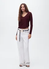 Jersey de punto fino color vino tinto, con cuello pico y manga larga. Tejido de lúrex con acabado brillante.