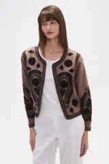 Chaqueta corta de algodón color marrón topo, sin cuello, con bordados florales y de estilo paisley en negro. Presenta un borde festoneado y mangas largas.