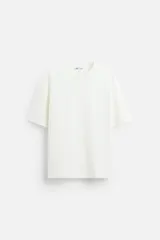Camiseta color blanco hueso, de corte holgado, cuello redondo y manga corta.