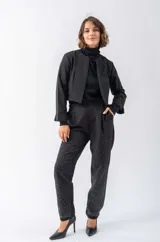 Chaqueta negra con cuello solapa, corte irregular y mangas largas con apliques de strass.