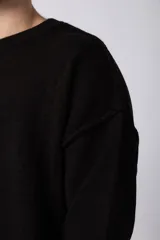 Sweater negro de tejido de punto grueso, corte holgado y cuello redondo.