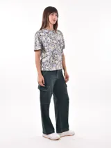 Pantalón cargo de mujer color beige claro, tiro medio/alto, corte ancho y recto, con bolsillos laterales tipo parche en las piernas.