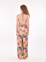 Mono largo blanco con textura plisada, escote halter y aberturas laterales en la pierna. Incluye un lazo fino para ajustar a la cintura.