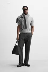 Pantalón chino negro slim fit confeccionado en tejido técnico de secado rápido. Cuenta con bolsillos frontales y traseros de vivo. Cierre frontal con cremallera y botón.