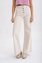 Pantalón de jean color beige, de corte palazzo, con bolsillos delanteros con botón y cintura alta.