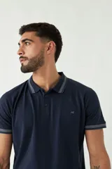 Chomba azul marino de manga corta con cuello polo y detalles de líneas grises en cuello y mangas. Tiene logo bordado en el pecho. Corte regular.