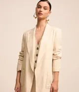 Blazer largo color beige confeccionado en viscosa y lino, con cuello solapa, bolsillos y forro estampado a rayas.