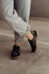 Zapatillas bajas color beige con estampado de piel de serpiente metalizada, cordones blancos y suela color caramelo.