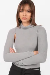 Body gris de tejido de punto con cuello alto y mangas largas. Presenta aberturas en los hombros y broches en la entrepierna.