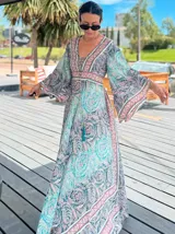 Vestido largo de polysilk con estampado paisley en tonos azul, celeste y dorado. Tiene escote en V, mangas largas acampanadas y corte amplio.