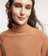 Blusa de punto color blanco, con cuello alto, manga larga y diseño liso.