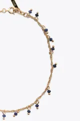 Set de tres pulseras tobilleras metálicas doradas con abalorios de diferentes colores y formas.