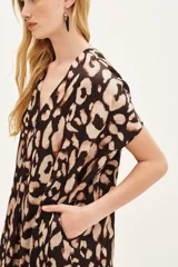 Vestido midi estampado animal print, con cuello en V y manga corta ancha. Presenta un calce holgado y bolsillos laterales.