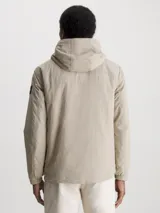 Campera beige con capucha, cierre frontal con cremallera, bolsillos laterales con cremallera y logo de Calvin Klein en la manga.