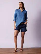 Blusa celeste de lyocell con cuello a la base con solapa, escote en V y abertura central con botones. Manga 3/4 regulable con presilla y botón.