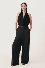 Pantalón negro de tiro alto con trabillas, confeccionado en mezcla de lana. Presenta bolsillos laterales, falsos bolsillos de doble vivo, cinturilla interior a contraste con pespuntes y raya planchada en el delantero. Cierre frontal con cremallera, botón interior y ganchos metálicos.