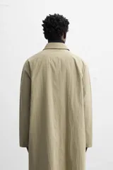Gabardina color beige de corte amplio, con cuello solapa, manga larga, bolsillos laterales con solapa y cierre frontal con botones.