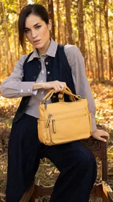 Cartera de cuero color borgoña, con correa larga regulable, dos bolsillos frontales con cierre y un bolsillo trasero con cierre.