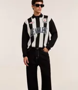 Pantalón baggy negro de sarga de algodón, con cintura fija con trabillas, botón contrastante y cierre por cremallera oculto, bolsillos laterales y traseros. Modelo holgado de corte recto y ancho.