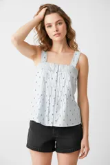 Blusa celeste con estampado de flores pequeñas, breteles anchos y escote cuadrado con detalle de puntilla. Cierre frontal con botones.