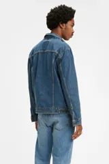 Campera de jean celeste de corte clásico, con cuello de punta, cierre frontal con botones metálicos, mangas largas con puños abotonados, bolsillos con solapa abotonados en el pecho y bolsillos laterales.
