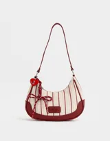 Bandolera hobo de cuerina color crema con rayas verticales rojas, asa corta de hombro y charm colgante. Tiene cierre superior y tag frontal con logo "The Brunch Club".