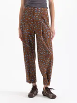 Pantalón de popelina con lycra color marrón, con estampado exclusivo de boquitas dinámicas en azul. Presenta pinzas en la cintura y el ruedo para un ajuste slim mom, cintura trasera elástica, bolsillos ojal en la espalda y bolsillos ocultos en los laterales. El acceso es mediante broche, cierre y botón interno a tono.