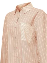 Camisa de manga larga color beige con rayas verticales blancas, cuello camisero, cierre con botones y bolsillo en el pecho. Confeccionada en lino orgánico y algodón orgánico.