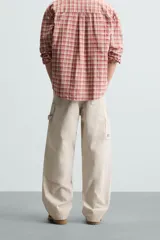 Pantalón gris de corte relaxed fit, con cinco bolsillos, efecto lavado, aplicación de tira y bolsillo multifunción en perneras. Cierre frontal con cremallera y botón.