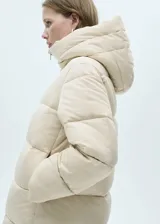 Campera puffer larga color beige, con capucha, cierre frontal con cremallera y bolsillos laterales con cierre.