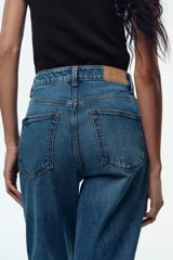 Jeans de tiro alto color celeste, corte mom fit, con cinco bolsillos y cierre frontal con cremallera y botón.