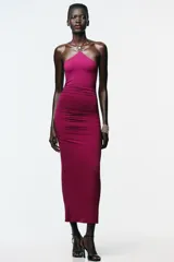 Vestido color fucsia de poliamida con cuello halter con lazada y detalle de aplicación metálica en forma de sol.