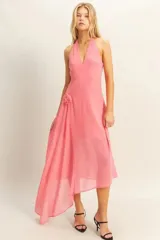 Vestido midi de fiesta color rosa coral, con escote halter, espalda descubierta y falda asimétrica con detalle de flor en la cintura.