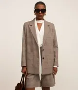 Blazer oversized con estampado de cuadros, cierre simple con dos botones, solapas de muesca y bolsillos delanteros con solapa.