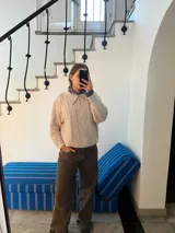 Sweater color beige tejido en lana simil cashmere, con cuello polo y cartera abotonada.