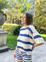 Remera de punto color beige con rayas azules, de corte suelto y mangas cortas.