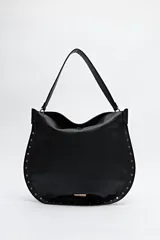 Bolso negro tipo hobo de símil cuero con textura suave, correa al hombro y detalle de tachas metálicas en los bordes.