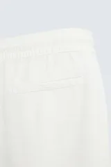 Bermuda de algodón color marrón oscuro, de corte regular fit, con cintura elástica ajustable mediante cordón. Presenta bolsillos laterales y un bolsillo trasero de vivo.