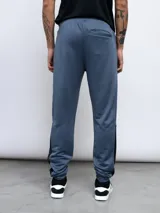 Pantalón de jogging gris claro con recortes laterales en gris oscuro, logo de Umbro estampado en el muslo y cintura ajustable con cordón. Confeccionado en tejido french terry de poliéster.