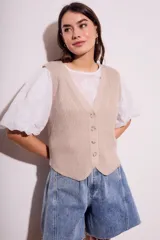 Chaleco de punto color beige con cuello en V y cierre frontal con botones.