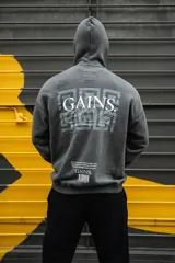 Canguro gris con capucha, confeccionado en algodón con felpa. Estampado en la espalda con la palabra "GAINS" en letras griegas y la frase "BE UNSTOPPABLE /// FOCUS".