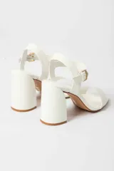 Sandalias de tacón alto color lila, con tira delantera y tobillera con hebilla dorada.