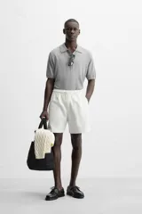 Bermuda negra regular fit confeccionada en tejido de algodón con estructura. Cintura elástica ajustable con cordón, bolsillos laterales y bolsillo trasero de vivo.