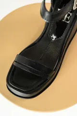 Sandalias de cuero color marrón con plataforma y taco de cuña. Tiras anchas con textura tipo cocodrilo y hebilla metálica plateada.