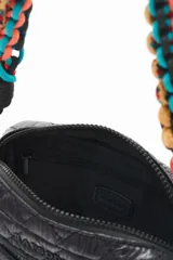 Bandolera negra de nylon matelassé con correa larga regulable y correa corta desmontable de cordones trenzados multicolores. Tiene cierre superior, bolsillo frontal con cierre, bolsillo trasero y dos bolsillos internos.