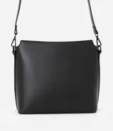 Bolso mediano tipo postman color negro con textura en relieve de líneas horizontales. Tiene correa larga regulable, cierre con cremallera y forro de poliéster.