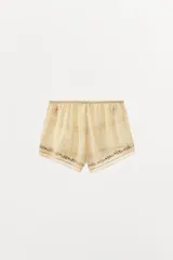 Shorts color crema de tiro alto con cintura elástica, bordados florales y puntilla a tono.