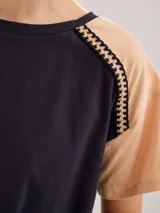 Remera negra de algodón con mangas cortas con detalle de calado y bordado en los hombros y mangas. Corte recto con cintura ajustable con cordón.